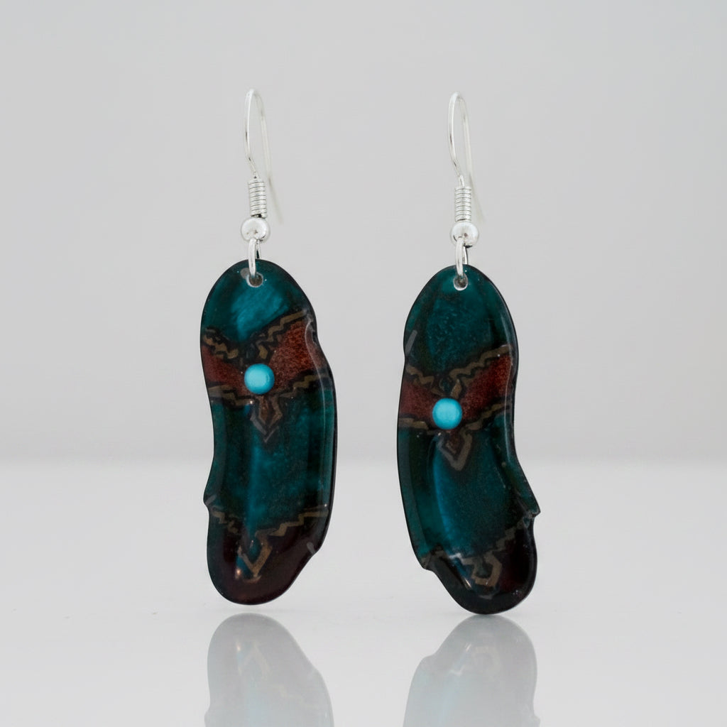 A pair of handmade glass drop earrings featuring organic, irregular shapes in deep teal, black, and brown, accented with a small turquoise bead and silver fishhook wires.