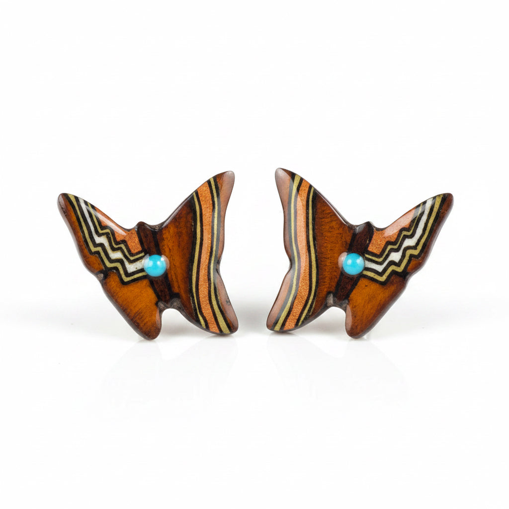 A pair of hand-painted brown butterfly earrings made from moose antler, with black, beige, and turquoise patterns.